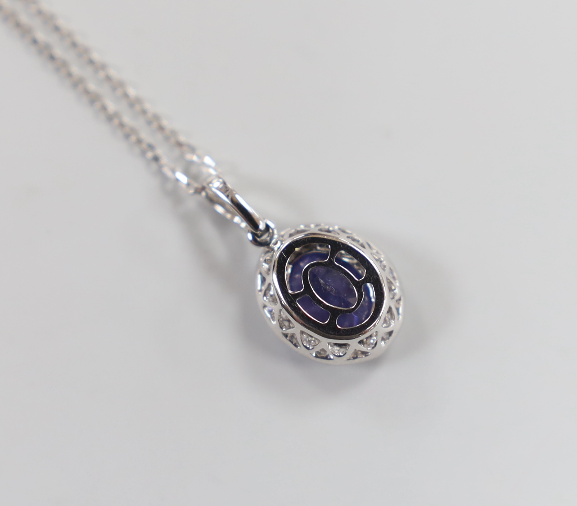A modern 18k white metal, tanzanite and diamond set oval cluster pendant, 20mm, on a 750 fine link chain, 39cm, gross weight 3.2 grams, the tanzanite weighing approx. 1.70ct, the diamonds totalling approx. 0.50ct